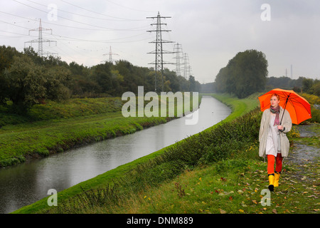 Oberhausen, Allemagne, une jeune femme marche dans la pluie avec parapluie marchant le long de l'Emscher Banque D'Images