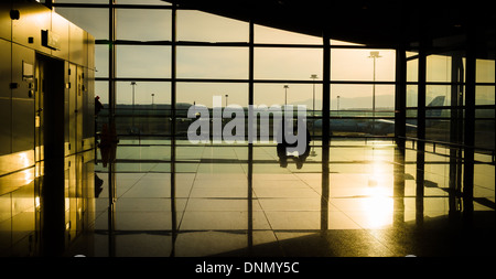 L'Aube à l'aéroport de Kuala Lumpur avec soleil à travers de grandes fenêtres et la silhouette du couple sitting on floor Banque D'Images