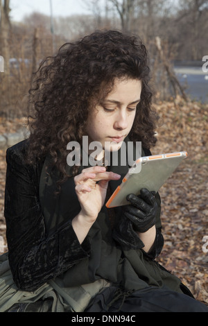 Jeune femme utilise son ipad mini, assis dans le parc de Brooklyn, New York. Banque D'Images