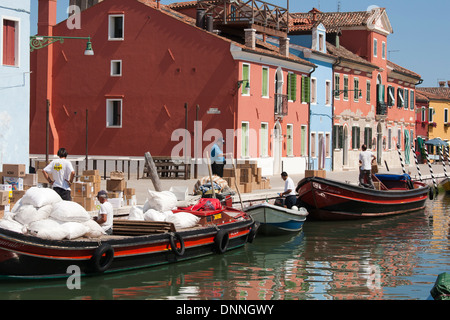 Burano - hommes le déchargement d'un navire en face de maisons colorées sur l'île de Burano, lagune de Venise, Italie Banque D'Images