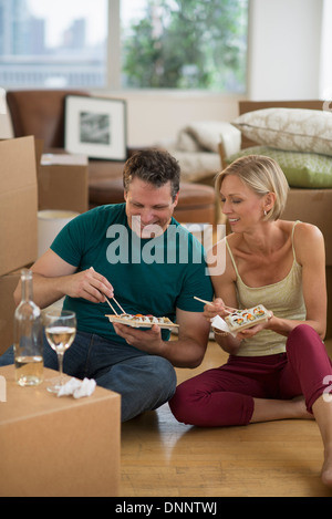 Couple eating sushi in new home Banque D'Images