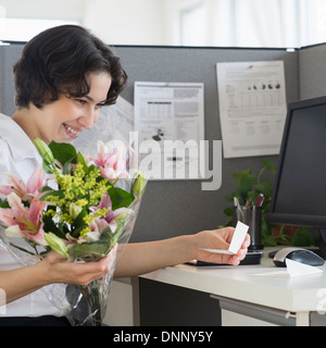 Woman holding bouquet in office Banque D'Images