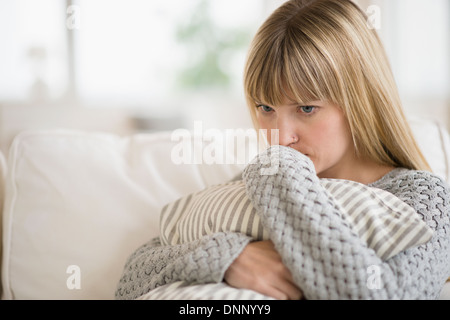 Femme assise sur un canapé et la pensée Banque D'Images