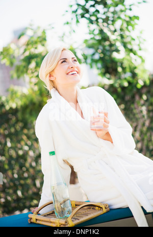 Teenage girl (16-17) wearing bathrobe sitting in garden Banque D'Images