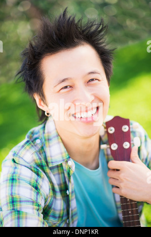 Portrait of teenage boy (16-17) en jouant de la guitare dans le parc Banque D'Images