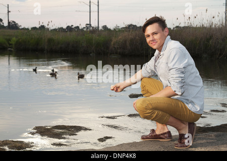 Jeune homme nourrir les canards Banque D'Images