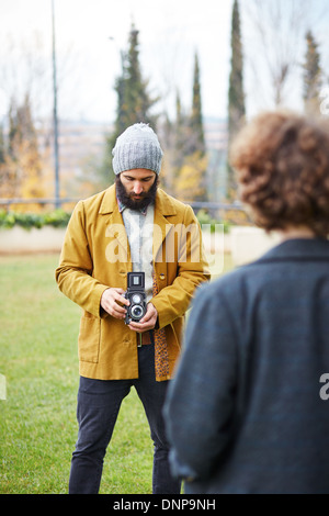 Les jeunes de prendre la photo pour hipster barbu redhead girl avec TLR appareil photo à l'extérieur Banque D'Images