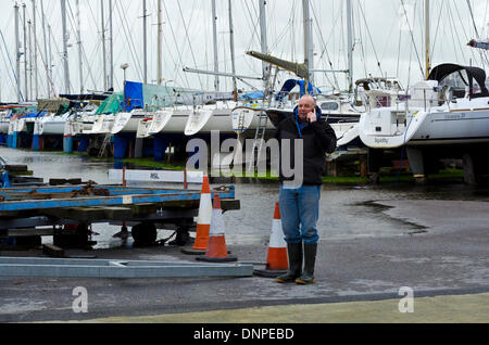 Christchurch, Dorset, UK. 06Th Jan, 2014. Elkins boatyard sur Christchurch Quay inondée après de fortes pluies, rivière Stour à briser ses rives et aggravée par une forte marée de vive-eau. Bateaux pour l'hiver dehors tendit maintenant entouré par l'eau. Mathew Elkins patrouillant la cour et prend en charge des contrôles en vertu de bateaux alors que la réception des appels des propriétaires inquiets Crédit : Roger Allen Photography/Alamy Live News Banque D'Images