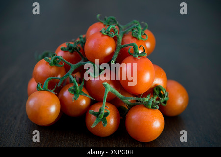 Tomates cerises sur une planche en bois foncé Banque D'Images