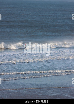 Un surfeur solitaire une vague au large de la côte nord du Devon à Putsborough. Cette côte est très prisée des surfeurs au Royaume-Uni Banque D'Images