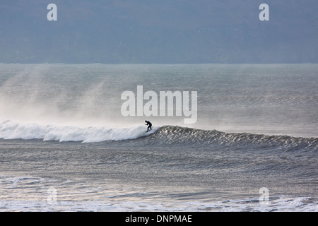 Un surfeur cresting une vague à Woolacombe Bay dans le Nord du Devon, Angleterre. Cette partie du littoral est populaire parmi les surfeurs à UK Banque D'Images