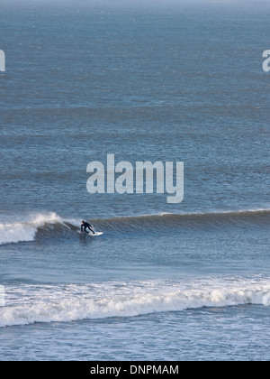 Un surfeur solitaire une vague au large de la côte nord du Devon à Putsborough. Cette côte est très prisée des surfeurs au Royaume-Uni Banque D'Images