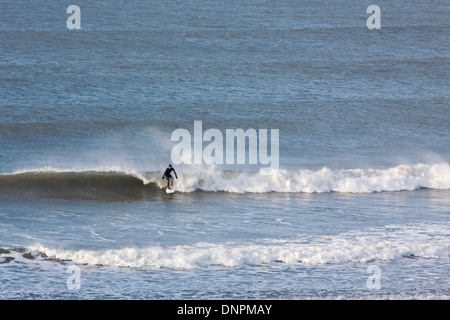 Un surfeur solitaire une vague au large de la côte nord du Devon à Putsborough. Cette côte est très prisée des surfeurs au Royaume-Uni Banque D'Images