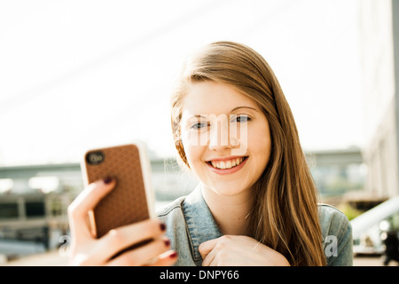 Young woman outdoors looking at smartphone Banque D'Images