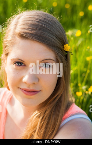 Close-up portrait of young woman sitting in field with flower in hair, Allemagne Banque D'Images