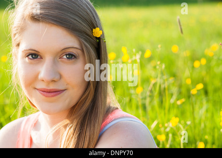 Close-up portrait of young woman sitting in field with flower in hair, Allemagne Banque D'Images