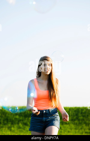 Young woman walking in field jouant avec les bulles, Allemagne Banque D'Images