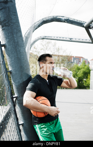 Couple sur le terrain extérieur de basket-ball de boire une bouteille d'eau, de l'Allemagne Banque D'Images