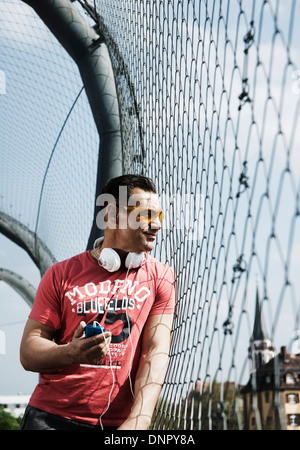 Couple sur le terrain extérieur de basket-ball holding MP3 player, Allemagne Banque D'Images