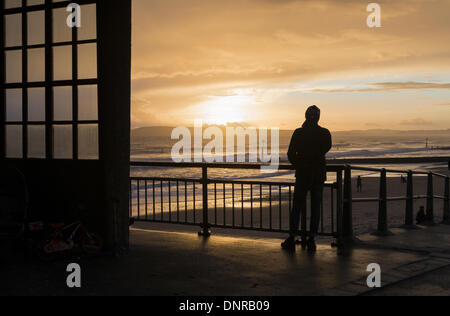 Silhouette of man en regardant le coucher du soleil de Boscombe pier dans le Dorset Samedi 4 Janvier 2014 Banque D'Images