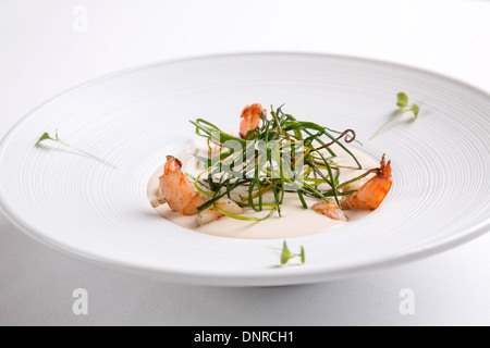 Soupe à la crème aux crevettes dans une plaque ronde blanche sur fond blanc Banque D'Images