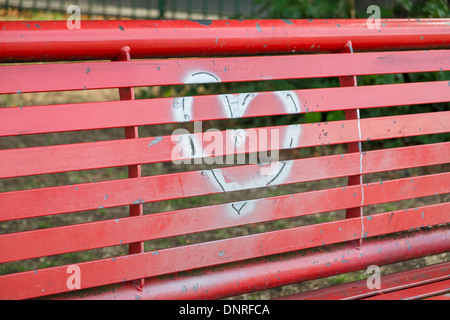 Un graffiti d'argent coeur sur un banc rouge Banque D'Images