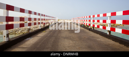 Un pont à Bonaire en rouge et blanc main courante des deux côtés et la route dans la distance semble durer pour toujours. Banque D'Images