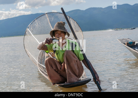 Pêcheur traditionnel sur le lac Inle tient fièrement les petits poissons pris en piège conique assis sur son bateau le 3 novembre 2013 Banque D'Images