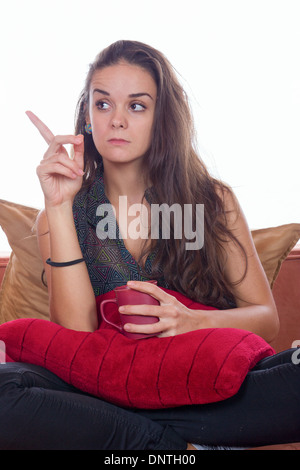 Femmes menacées tout en étant assis sur le canapé avec une tasse de café Banque D'Images