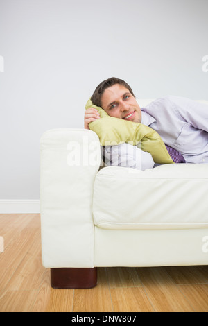 Smiling young woman lying on sofa in living room Banque D'Images