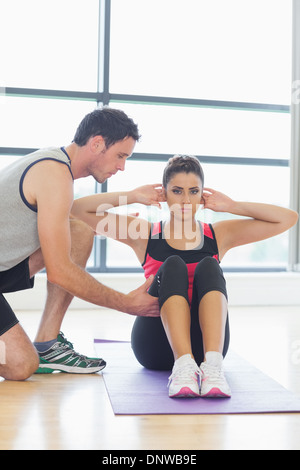 Trainer assisting woman avec pilate exercises in fitness studio Banque D'Images