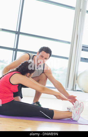 Trainer assisting woman avec pilate exercises in fitness studio Banque D'Images