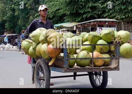 Un homme vend grand coco à partir d'un panier sur une rue de ville de Phnom Penh, Cambodge. Banque D'Images