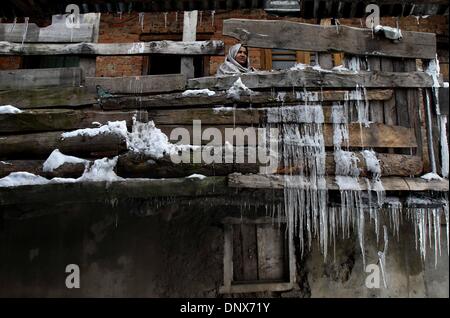 Srinagar, au Cachemire sous contrôle indien. 6 janvier, 2014. Une femme du Cachemire ressemble sur de sa maison avec des glaçons pendant de l'escrime à l'Kokernag en bois, à environ 80 kilomètres au sud de la ville de Srinagar, la capitale d'été du Cachemire sous contrôle indien, le 6 janvier 2014. Les parties plus froides du Cachemire sous contrôle indien a reçu la semaine dernière une importante chute de neige, qui a suspendu la circulation routière, ferroviaire et aérienne dans la région. La région est sous l'emprise de la vague de froid et de l'imd locales ont prévu plus de neige mercredi. Credit : Javed Dar/Xinhua/Alamy Live News Banque D'Images