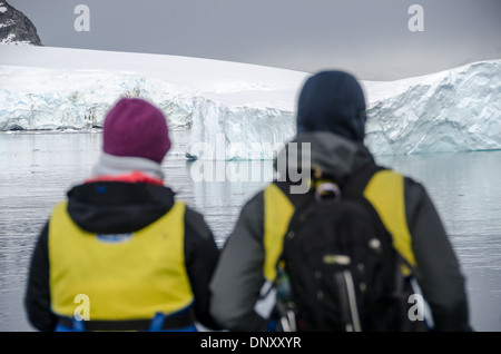 Passagers de l'île de Cuverville bateaux Zodiac Péninsule Antarctique // les passagers prêts dans leurs gilets de sauvetage admirent la vue sur le paysage en attendant d'embarquer sur des bateaux pneumatiques Zodiac pour se rendre à terre sur l'île de Cuverville sur le côté ouest de la péninsule Antarctique. Banque D'Images