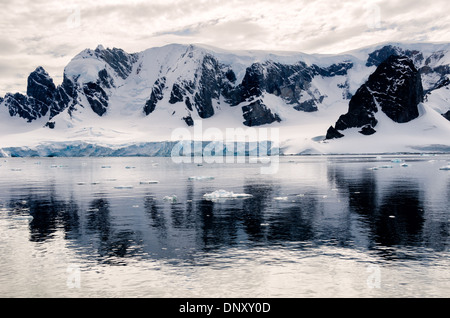 L'ANTARCTIQUE - Montagnes rocheuses escarpées réfléchir sur les eaux encore près de Cuverville Island sur la péninsule antarctique. Banque D'Images