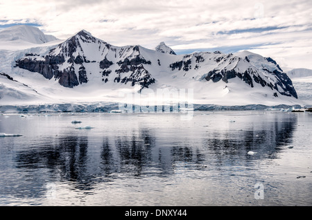 L'ANTARCTIQUE - Montagnes rocheuses escarpées réfléchir sur les eaux encore près de Cuverville Island sur la péninsule antarctique. Banque D'Images