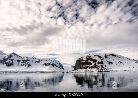 L'ANTARCTIQUE - Montagnes rocheuses escarpées réfléchir sur les eaux encore près de Cuverville Island sur la péninsule antarctique. Banque D'Images