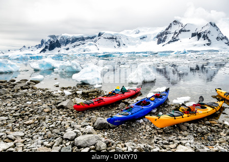 L'ANTARCTIQUE - des kayaks tandem tiré vers le haut sur le rivage rocailleux parmi les icebergs et brash à Cuverville Island sur la péninsule antarctique. Banque D'Images