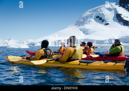 ÎLE de Cuverville, Antarctique — les kayakistes s'arrêtent pour admirer les paysages à couper le souffle par une journée ensoleillée et claire à l'île de Cuverville, sur la péninsule Antarctique. Le paysage immaculé de montagnes enneigées, de glaciers et d'eaux calmes offre une toile de fond magnifique à ces aventuriers qui explorent l'un des endroits les plus reculés et les plus beaux de la Terre. Banque D'Images