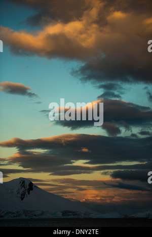 L'ANTARCTIQUE - le soleil couchant jette une lueur orange magnifique sur les nuages et les montagnes de l'Antarctique spectaculaire paysage de Paradise Harbour, l'Antarctique. Banque D'Images