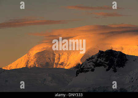 L'ANTARCTIQUE - le soleil couchant jette une lueur orange magnifique sur les nuages et les montagnes de l'Antarctique spectaculaire paysage de Paradise Harbour, l'Antarctique. Banque D'Images