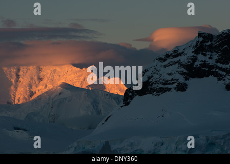 L'ANTARCTIQUE - le soleil couchant jette une lueur orange magnifique sur les nuages et les montagnes de l'Antarctique spectaculaire paysage de Paradise Harbour, l'Antarctique. Banque D'Images