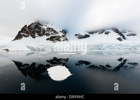 LEMAIRE CHANNEL, Antarctique — des reflets miroirs parfaits de montagnes et de falaises à Glandaz point sur Booth Island créent une scène symétrique dans les eaux exceptionnellement calmes. Ces conditions vitreuses dans le canal Lemaire, surnommé « Kodak Gap », sont rares dans cette région typiquement balayée par le vent de la péninsule Antarctique. Les eaux calmes créent un miroir naturel du paysage antarctique spectaculaire. Banque D'Images