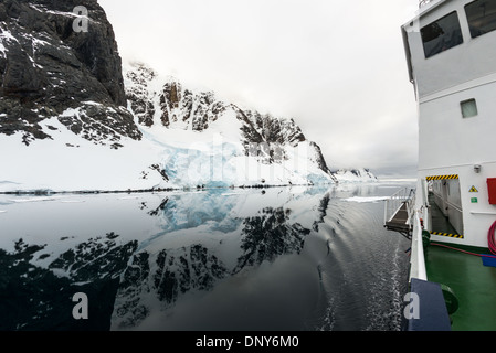 L'ANTARCTIQUE - une croisière antarctique navire passe par les eaux miroitantes du Canal Lemaire, comme les montagnes le long de la côte se reflètent sur l'eau. Le Canal Lemaire est parfois appelée 'gap' Kodak dans un clin d'œil à son célèbre vue panoramique. Banque D'Images