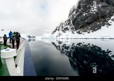 L'ANTARCTIQUE - une croisière antarctique navire passe par les eaux miroitantes du Canal Lemaire, comme les montagnes le long de la côte se reflètent sur l'eau. Le Canal Lemaire est parfois appelée 'gap' Kodak dans un clin d'œil à son célèbre vue panoramique. Banque D'Images