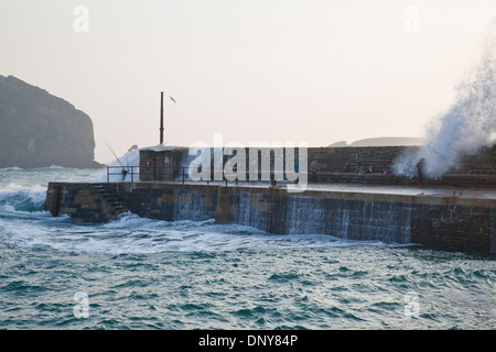 Un accident de près avec des vagues qui s'écrasant au-dessus de personnes pêchant sur le mur du port, port de Mullion Cove, péninsule de Lizard, Cornwall, Royaume-Uni. Banque D'Images