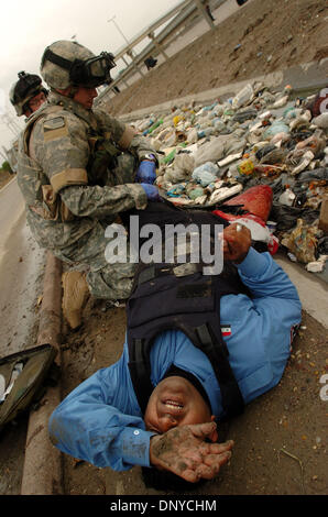 Jan 26, 2006 ; Abu Ghraib, Bagdad, l'Iraq ; un agent de police iraquiens blessés réagit comme la CPS. CHRIS SCHWARZ, infirmier au 1er Escadron, 71e Régiment de cavalerie, applique un pansement à la jambe. L'IP a été blessé dans une fusillade en voiture par des insurgés sur son convoi. Le convoi IP a riposté. Un insurgé a été trouvé mort dans une voiture criblée de balles, qui correspondait à la description de l'action, a été f Banque D'Images