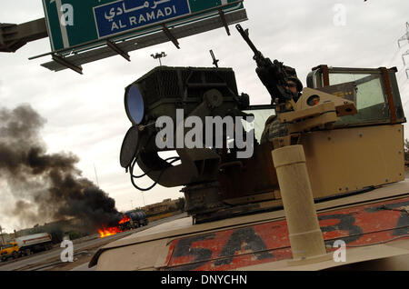 Jan 26, 2006 ; Abu Ghraib, Bagdad, Iraq, un camion-citerne de gaz brûle sur une autoroute Bagdad comme un soldat américain du 1er Escadron, 71e Régiment de cavalerie, surveille la circulation à Bagdad le 26 janvier 2006. Les insurgés arrêtés quatre camions à gaz et mis le feu à trois. L'une a brûlé complètement ; les deux autres ont été mis en œuvre par les pompiers locaux. Les insurgés en Irak sont en train d'attaquer les réserves pétrolières du pays et g Banque D'Images