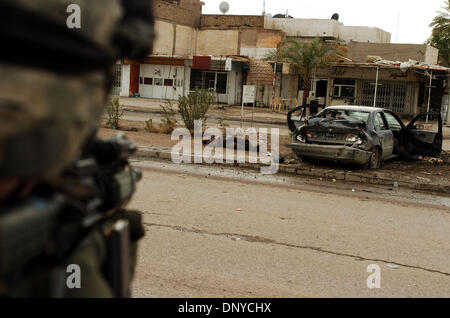 Jan 26, 2006 ; Abu Ghraib, Bagdad, Irak, un soldat américain vise sa carabine M-4 à un insurgé blessé à Bagdad le Jan 26, 2006. Les soldats ont pensé que l'homme avait une grenade à main et attendaient la police iraquienne lui de vérifier avant de commencer le traitement. Il est décédé plus tard à l'hôpital. Les soldats américains à partir de 1-71 Cavalry tourné la voiture après les quatre insurgés ont attaqué leur patro Banque D'Images